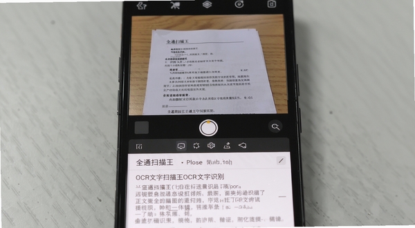 全通扫描王OCR文字识别界面,手机屏幕上半部分为拍摄的纸质文档图片,下半部分为提取出的可编辑文字内容,背景为简洁的浅灰色桌面,突出文字提取的实用价值