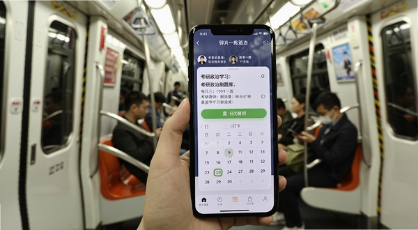 考研政治刷题库每日一练界面,手机屏幕显示推送题目与打卡日历,背景为地铁车厢与手持手机场景,体现碎片化学习