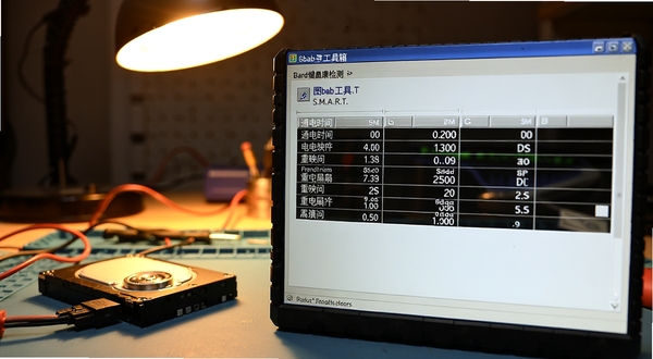 图吧工具箱硬盘健康检测界面特写,屏幕显示S.M.A.R.T.信息表格,包含通电时间与重映射扇区计数等条目,背景是维修工作台上的硬盘和连接线,主体位于画面中央偏右,背景为暖色调工作灯照明,写实摄影风格