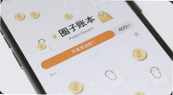 圈子账本 预算提醒界面 手机屏幕特写 预算进度条呈橙色预警状态 背景为浅灰色 有金币与购物袋小图标点缀 画面清爽 突出圈子账本预算管理功能
