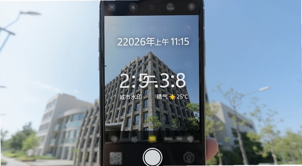 水印相机编辑水印实时水印叠加功能展示图,画面展示手机拍摄界面,取景框内一栋建筑物照片上清晰叠加了2026年日期、上午时间、城市地点和晴天气温信息,水印字体工整清晰,背景为明亮的户外场景,整体风格专业简洁