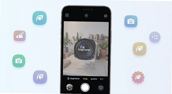 SnapCamer 应用主界面展示,画面中央为手机屏幕显示相机取景框,背景为浅色渐变,周围散落简约图标元素,整体风格清新科技感,突出 SnapCamer 品牌标识
