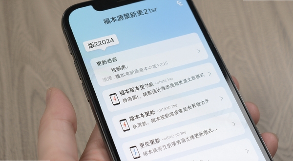 福本源最新版本更新界面展示,手机屏幕中显示版本更新日志列表,背景为浅蓝色渐变,界面中有版本号标签和更新内容条目,整体风格简洁商务