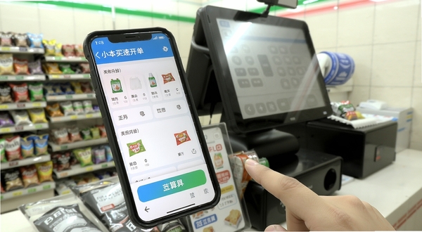 小本买卖快速开单界面,手机屏幕上展示商品列表和结算按钮,手指正在点击商品图标,背景是便利店收银台场景,光线明亮,细节清晰