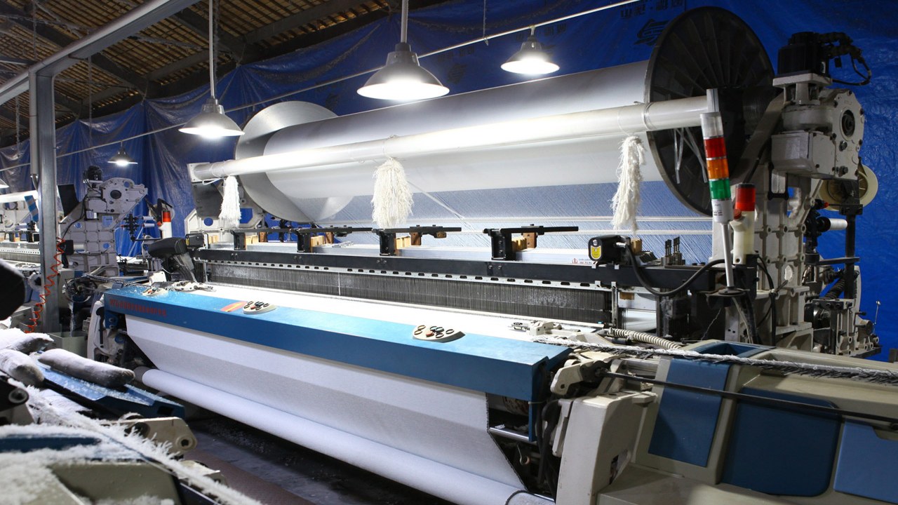现代高速自动织布机内部飞梭高速运转的工业摄影,体现机械精密与速度感