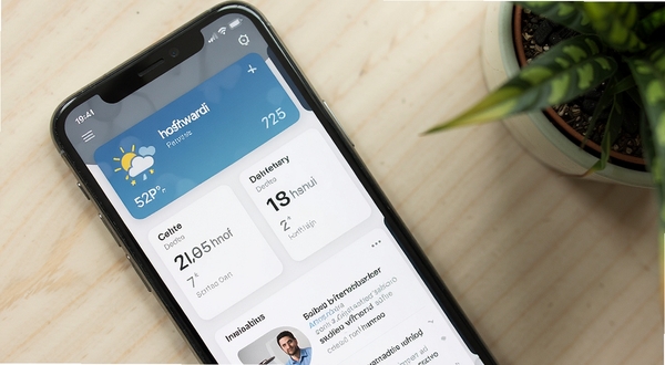 hooli 软件首页信息聚合界面特写,手机屏幕中显示天气卡片、日程卡片与资讯列表整齐排列,画面采用俯视微倾斜角度,背景为浅米色桌面与绿植一角,光线柔和自然,突出界面整洁有序
