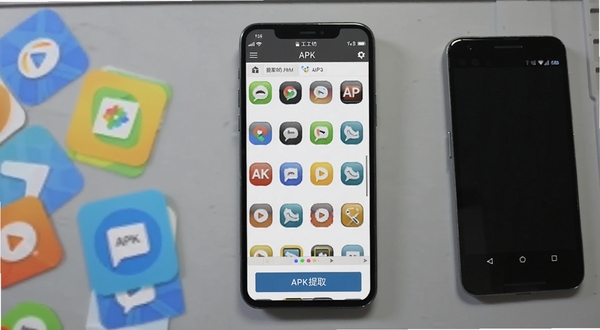 APK 图标工坊软件主界面截图,画面中央展示手机屏幕,屏幕内是图标工坊的图标列表与提取按钮,背景为浅灰色工作台桌面,左侧散落几个彩色应用图标卡片,右侧放置一部安卓手机,整体光线柔和,适合软件下载站展示图