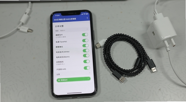 360应用权限设置与后台管理界面,手机屏幕显示权限开关列表与电池优化白名单设置页,旁边放置数据线和充电器,背景为浅灰桌面,风格写实清晰,突出设置操作场景