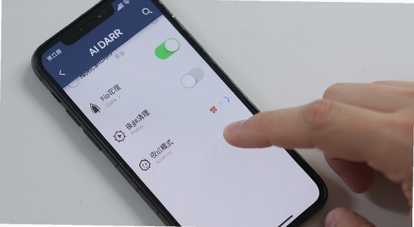一部智能手机屏幕显示AI日报应用的设置页面,页面中包含通知开关、缓存清理、夜间模式等选项,手机旁有一只手正在点击屏幕,背景为简洁的浅灰色桌面,画面聚焦于操作细节,光线明亮均匀,风格写实
