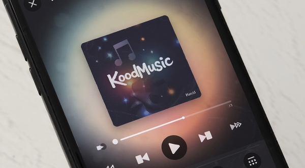 KoodMusic音乐播放器主界面,简洁深色主题,中央展示专辑封面与播放控制按钮,背景为柔和渐变光晕,手机屏幕特写视角,现代扁平化设计风格