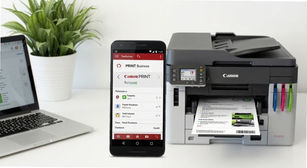 画面中央一部安卓手机屏幕显示Canon PRINT Business应用界面,手机右侧是一台佳能彩色激光打印机正在输出文件,背景为明亮整洁的现代办公桌面,左上角有绿植与笔记本电脑,整体色调清新专业,构图居中对称,突出移动打印的便捷场景