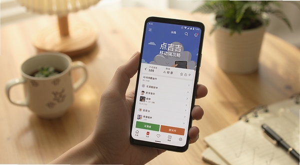 点吉移动端操作场景图,画面为一只手握持安卓手机,屏幕显示点吉应用正常运行的界面,背景为居家桌面环境,光线柔和,突出移动端使用攻略主题