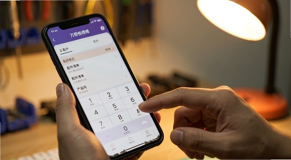 万帮修师傅 手机应用 费用登记页面 配件清单 数字键盘 维修师傅操作手机 特写 暖色灯光 真实使用场景
