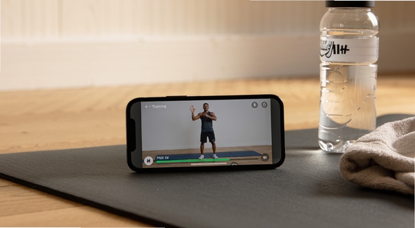 Nike+ Training Ӧ��ѵ��������д���ֻ����������ɫ�٤���ϣ���Ļ��ʾ����ʾ��������������������Ա߷���һƿˮ��һ��ë��������Ϊľ�ذ���ǳɫǽ�棬��Ȼ��Ӳ������룬������ů��ʵ�����־ӼҸ���ѵ���ĳ���