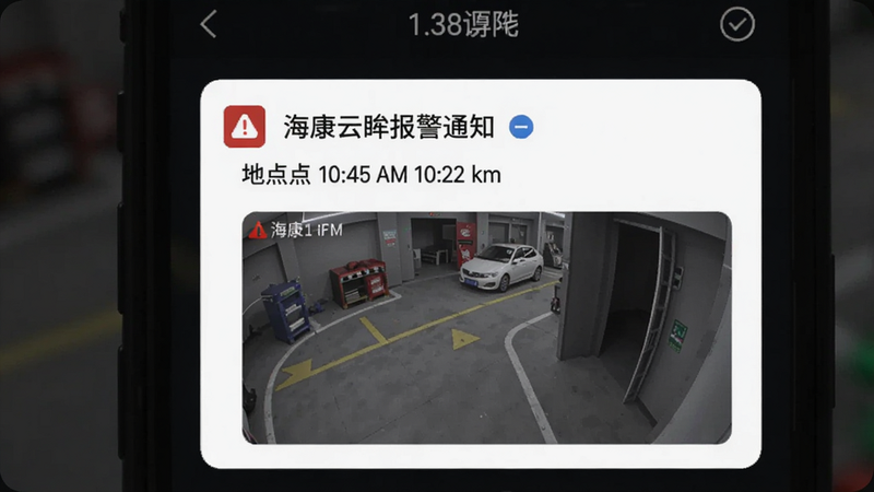 海康云眸报警通知界面,手机屏幕上显示一条报警消息,包含时间、地点和截图,背景为暗色,突出警示效果。