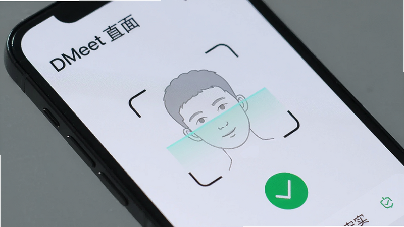 手机屏幕特写,显示DMeet直面身份认证界面,画面左上角有“DMeet 直面”字样,中间是一个正在扫描人脸的半透明轮廓,背景为浅色纹理,配以绿色对勾图标,强调安全真实,图片比例4:3。