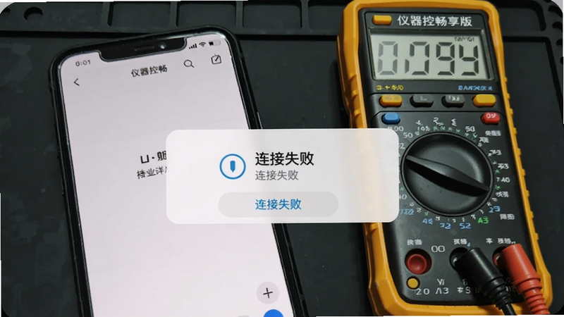 一张智能手机截图,显示仪器控畅享版的“连接失败”提示弹窗,旁边放置一个万用表,背景为深色工作台,突出故障排查场景
