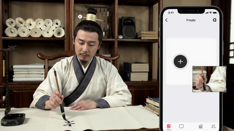 大秦艺术名师教学场景,一位穿汉服的老师面对镜头示范毛笔书写,画面右侧显示手机APP界面上的慢放按钮和局部放大框,背景是古色古香的书房,书架上有宣纸和砚台