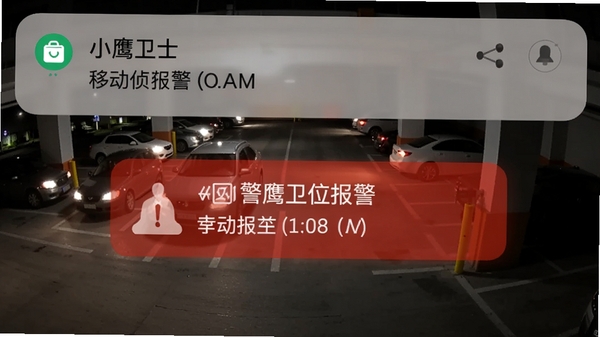 小鹰卫士报警推送界面,手机通知栏显示移动侦测报警,背景为夜晚的停车场监控视角,画面中有车辆灯光,突出警报信息的醒目显示
