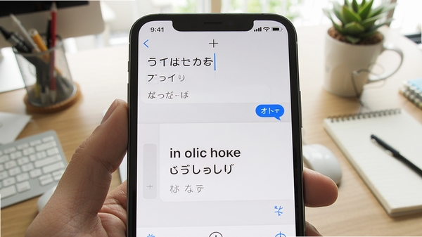 日语英语翻译应用内翻译对话界面,上方输入日语,下方显示英文结果,手机屏幕特写,背景为办公桌环境,光线明亮,细节丰富