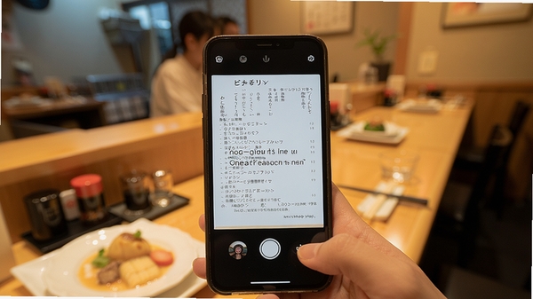 日语英语翻译拍照翻译功能演示,手机对准日文菜单,屏幕显示英文翻译结果,餐厅背景虚化,食物与菜单清晰可见,色彩自然