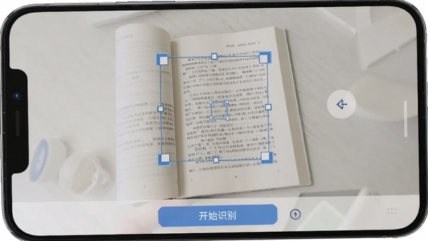 扫描文字提取软件文档矫正功能操作截图,手机界面显示一本打开的书籍,屏幕上的矩形矫正框覆盖在书页文字区域,界面下方有“开始识别”按钮,整体色调明亮干净