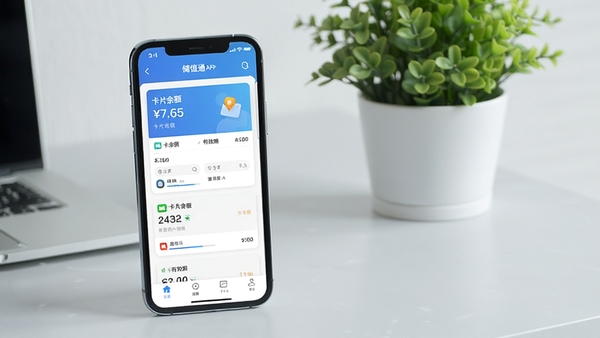 储值通APP界面预览图,画面主体为智能手机展示应用内卡片列表,背景为浅灰色桌面与绿植,整体风格简洁明亮,突出卡片余额与有效期信息