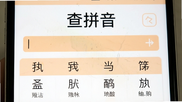 查拼音软件运行界面特写,中央显示“查拼音”字样和输入框,下方列出多个汉字的拼音对照结果,界面配色以白色和淡橙色为主,文字清晰,风格清新明快。