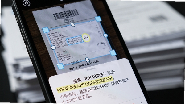PDF识别王APP的OCR识别功能特写,手机屏幕显示一张票据照片,识别框框住文字区域,下方弹出识别结果文本,文字高亮显示,背景有模糊的文档堆叠,画面细节丰富,突显技术感与实用性