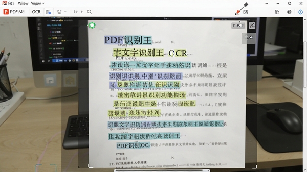 PDF识别王OCR文字识别功能演示,一张拍摄的纸质文档照片正在被软件处理,文字被高亮框选并转换为可编辑的文本,背景为办公桌和电脑,画面清晰展现识别过程