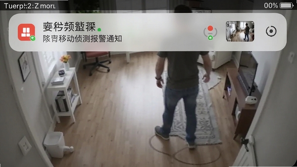 视频监控看家王移动侦测报警通知截图,手机通知栏显示报警消息和抓拍缩略图,背景为监控画面中有人走动的动态场景,突出智能报警功能