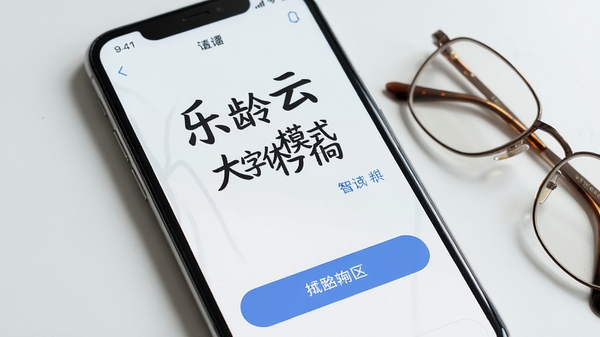 乐龄云大字体模式界面截图,手机上显示清晰放大的文字和按钮,背景为简洁的纯色,旁边放着一副老花镜,整体风格干净明亮,强调易读性