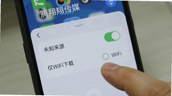 腾翔传媒使用教程配图,展示手机屏幕上的设置界面,包含“未知来源”开关和“仅WiFi下载”选项,背景为手机系统界面,手指点击操作,画面清晰,针对性强。