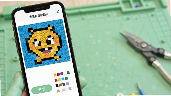 像素拼豆图助手预览与分享功能演示,手机屏幕显示一幅完成的像素画作品,下方有分享按钮与色号清单,背景为淡绿色工作台,整体风格清新,软件名称像素拼豆图助手清晰可见