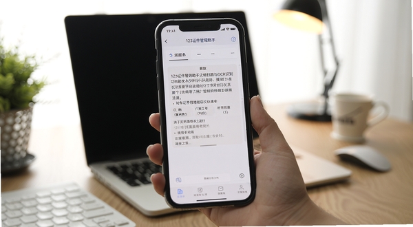 123证件管理助手文档扫描与OCR识别功能演示,手机屏幕显示文字提取结果,背景为办公桌面,光线柔和