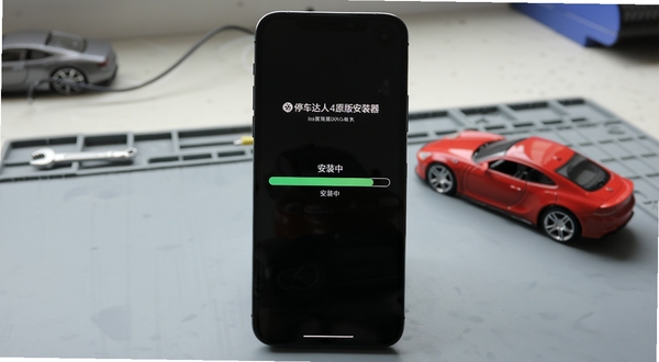 智能手机屏幕显示停车达人4原版安装器正在安装游戏的进度条画面,背景是干净的工作台,旁边有汽车模型,画面风格写实,突出安装过程的安全与流畅,图片中带有“安装中”状态提示