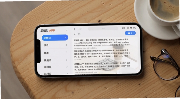 尼精彩APP界面横屏展示,左侧是分类资讯列表,右侧为详细文章页,背景使用淡雅的浅灰色,搭配蓝色高亮按钮,手机平放在原木色桌面上,旁边有一杯咖啡与眼镜,整体风格简约商务,突出软件的信息聚合与高效阅读体验。