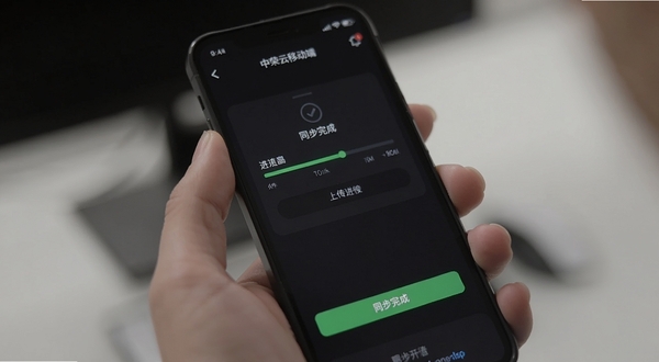 中荣云移动端操作界面截图,手机屏幕显示文件上传进度条与同步完成提示,界面为深色模式,背景为手持手机的特写,突出操作流程与状态反馈