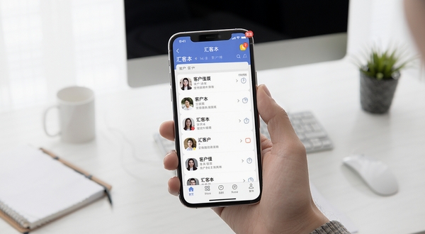汇客本移动端使用操作示意图,画面主体为手持手机展示应用主界面,背景区域为简约办公桌面,细节包括客户列表、底部导航栏和提醒角标,整体风格贴近真实使用场景