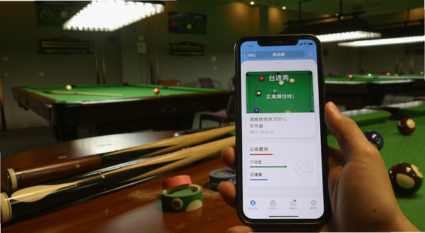 杆遇助教离线学习场景,手机屏幕显示台球技巧卡片与进度标记,背景为台球厅休息区,桌上有球杆与巧粉,整体光线柔和