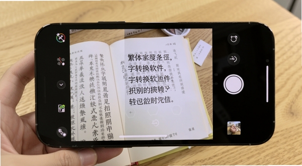 繁体字转换软件拍照识别功能演示图,手机摄像头对准一本繁体书籍,屏幕内实时显示识别出的文字并转换为简体,画面明亮清晰,背景为木质桌面,Boogu模型生成,写实风格,细节丰富