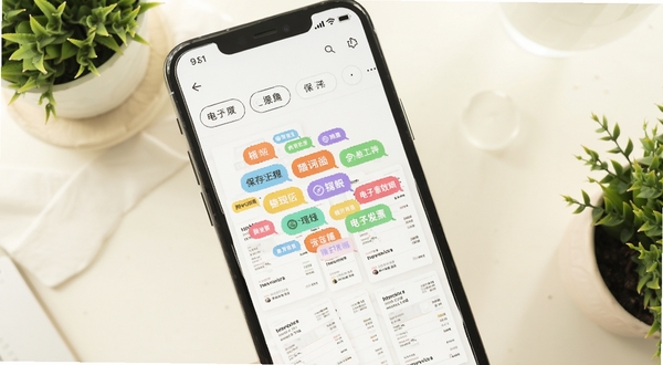 电子发票保存软件标签管理界面,画面主体为手机屏幕内彩色标签云与发票缩略图交错排列,背景区域为柔和米白色桌面与绿植点缀,屏幕中可见电子发票保存的标签筛选栏,画风清新明亮