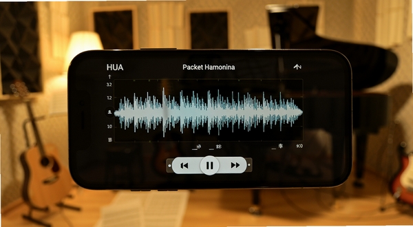HUA pocket harmonica录音回放功能界面,手机屏幕显示波形图和播放按钮,背景是音乐练习室的模糊轮廓,暖色调