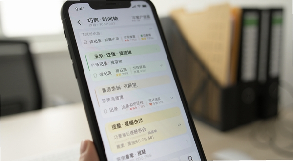 巧房应用内客户跟进时间轴界面特写,屏幕显示多条带看记录与提醒事项,背景虚化为办公桌面与文件夹,光线柔和,突出信息层级清晰