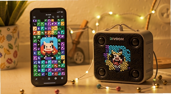点音App像素画板界面,手机屏幕显示彩色像素网格,旁边是Divoom像素音箱同步展示同款图案,桌面环境温馨,柔和暖光,细节清晰