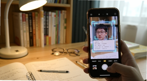 答题超人 拍照搜题功能演示 手机摄像头对准纸质试卷 屏幕上浮现识别框与答案预览 背景为书房桌面 光线柔和