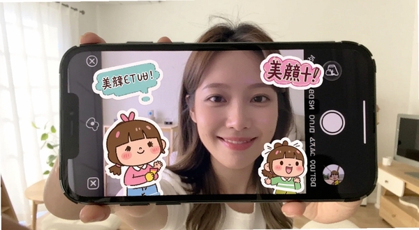 美颜自拍滤镜相机贴纸功能展示,手机屏幕中自拍照片上叠加了可爱的卡通贴纸和文字气泡,贴纸色彩鲜艳,人物笑容自然,背景为明亮的室内环境,整体氛围轻松愉快