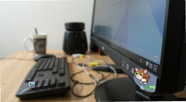 邦戈猫PC电脑版系统托盘静默运行示意图,画面主体为电脑屏幕右下角系统托盘区域,邦戈猫图标清晰可见,旁边有内存占用极低的绿色指示条,背景为模糊的办公桌面