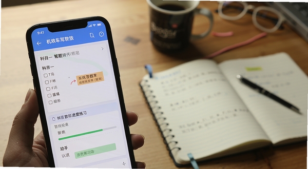 机动车驾驶人互联网学习软件题库练习界面特写,画面主体为手机屏幕展示科目一选择题与答题卡,背景区域为书房桌面与笔记本,整体风格专注学习氛围,细节包含错题标记与进度条,适合Boogu模型生成