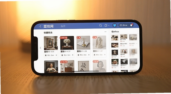 盟拍网移动端操作界面截图,展示拍卖列表与收藏夹页面,手机横屏放置于木质桌面,背景为柔和暖光,界面清晰显示拍品缩略图和倒计时标签,突出盟拍网日常使用场景